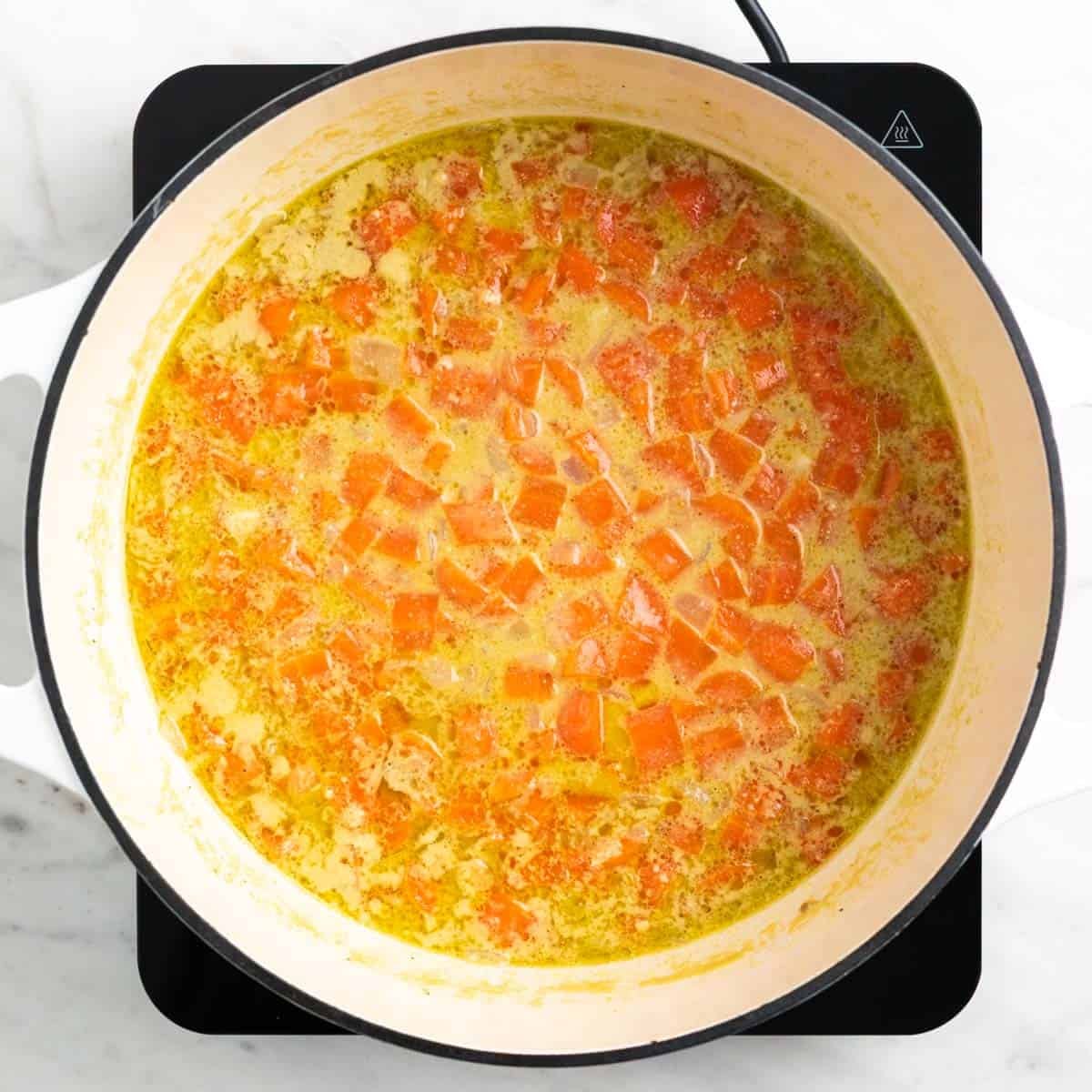 Vegan carrot soup cooked in a pot before blending