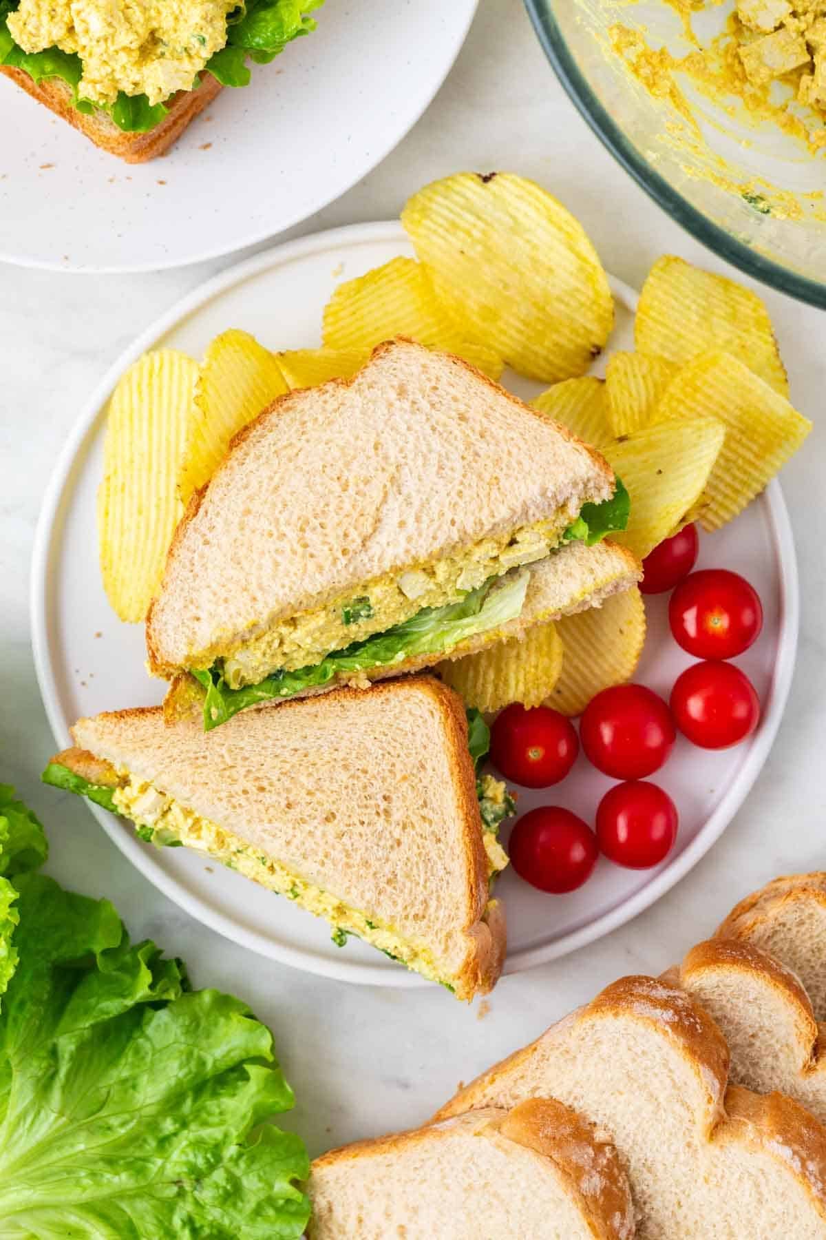 Vegan egg salad sandwiches served with cherries and potato chips