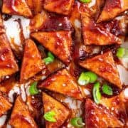 Crispy baked BBQ tofu triangles topped with sesame seeds and sliced green onions