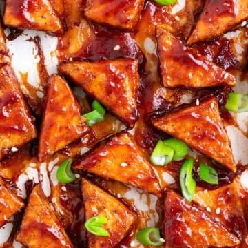 Crispy baked BBQ tofu triangles topped with sesame seeds and sliced green onions