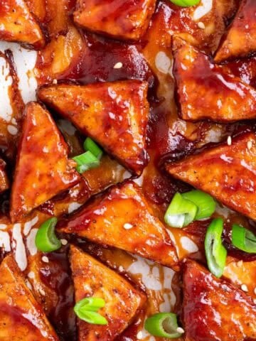 Crispy baked BBQ tofu triangles topped with sesame seeds and sliced green onions