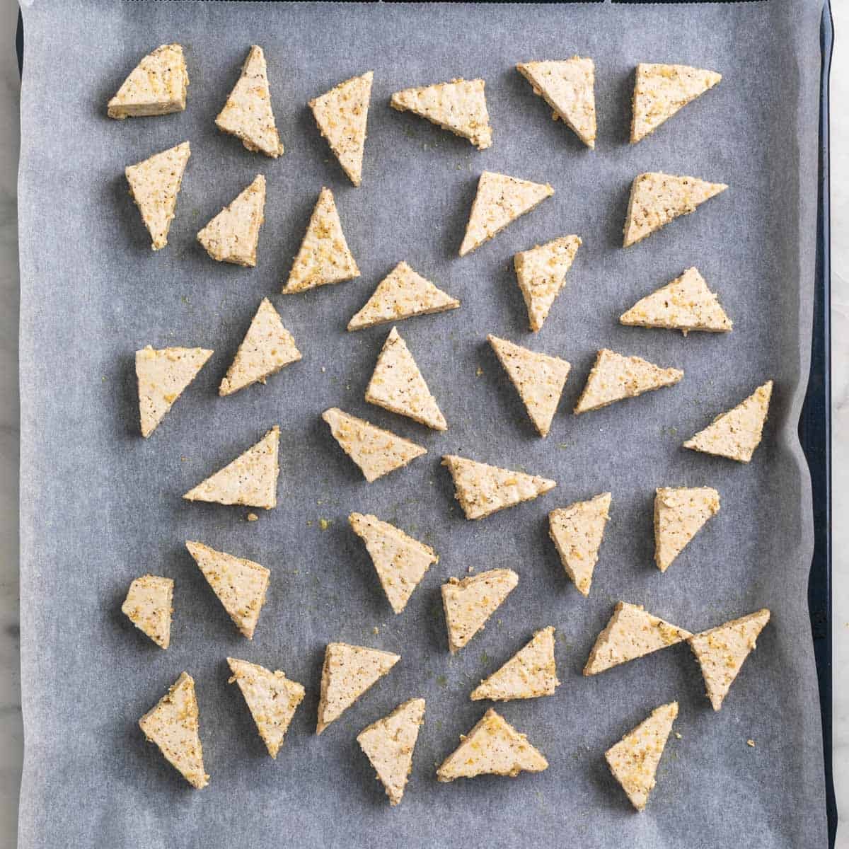 Tofu triangles on a baking sheet lined with parchment paper