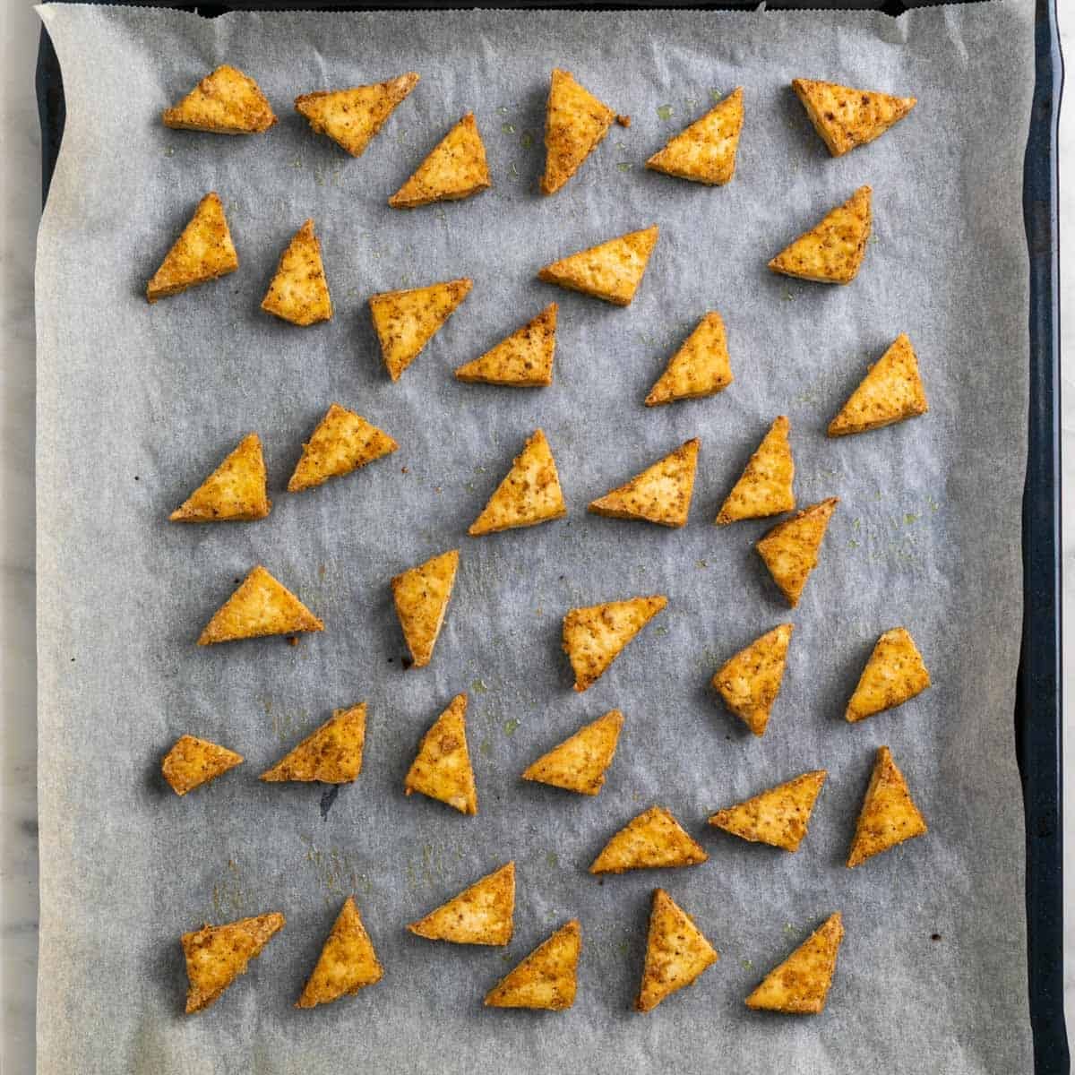 Baked tofu triangles on a baking sheet