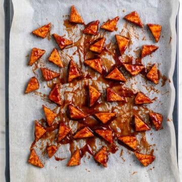 Baked tofu triangles coated with BBQ sauce before baking