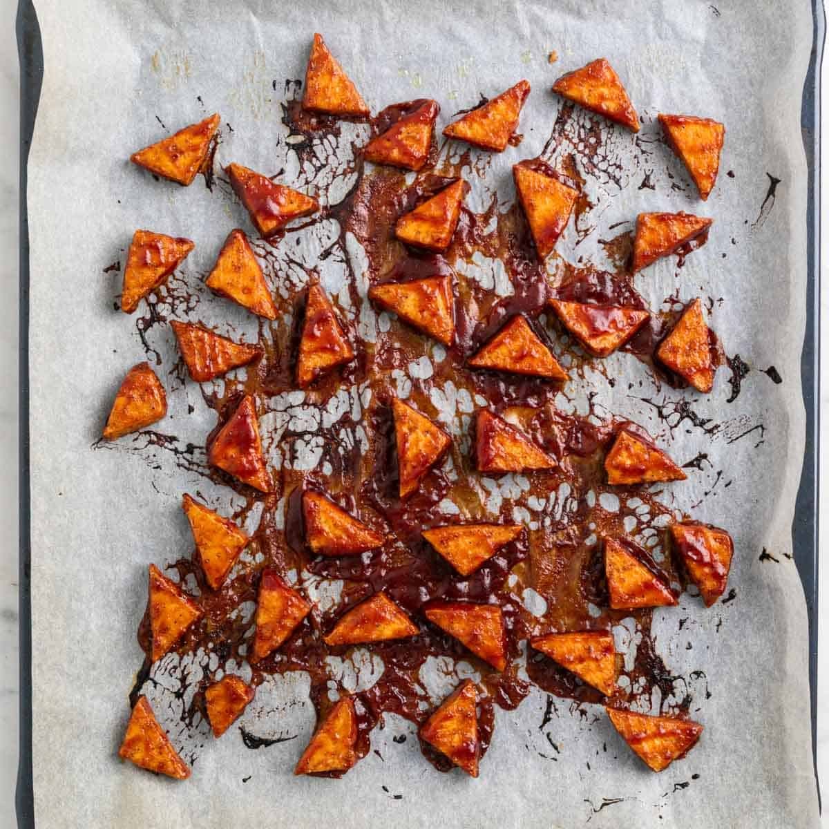 Baked BBQ tofu triangles on a baking sheet