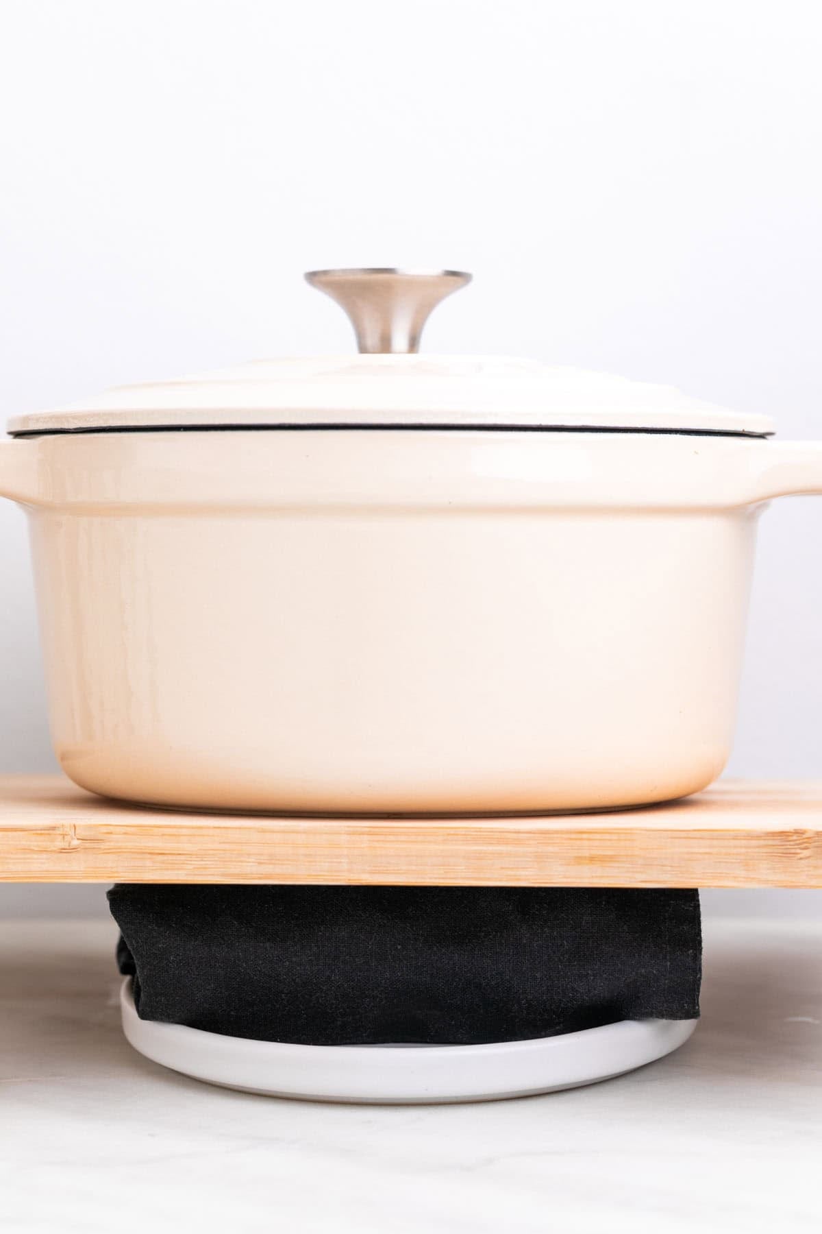 Tofu being pressed with a kitchen towel and a heavy pot on top