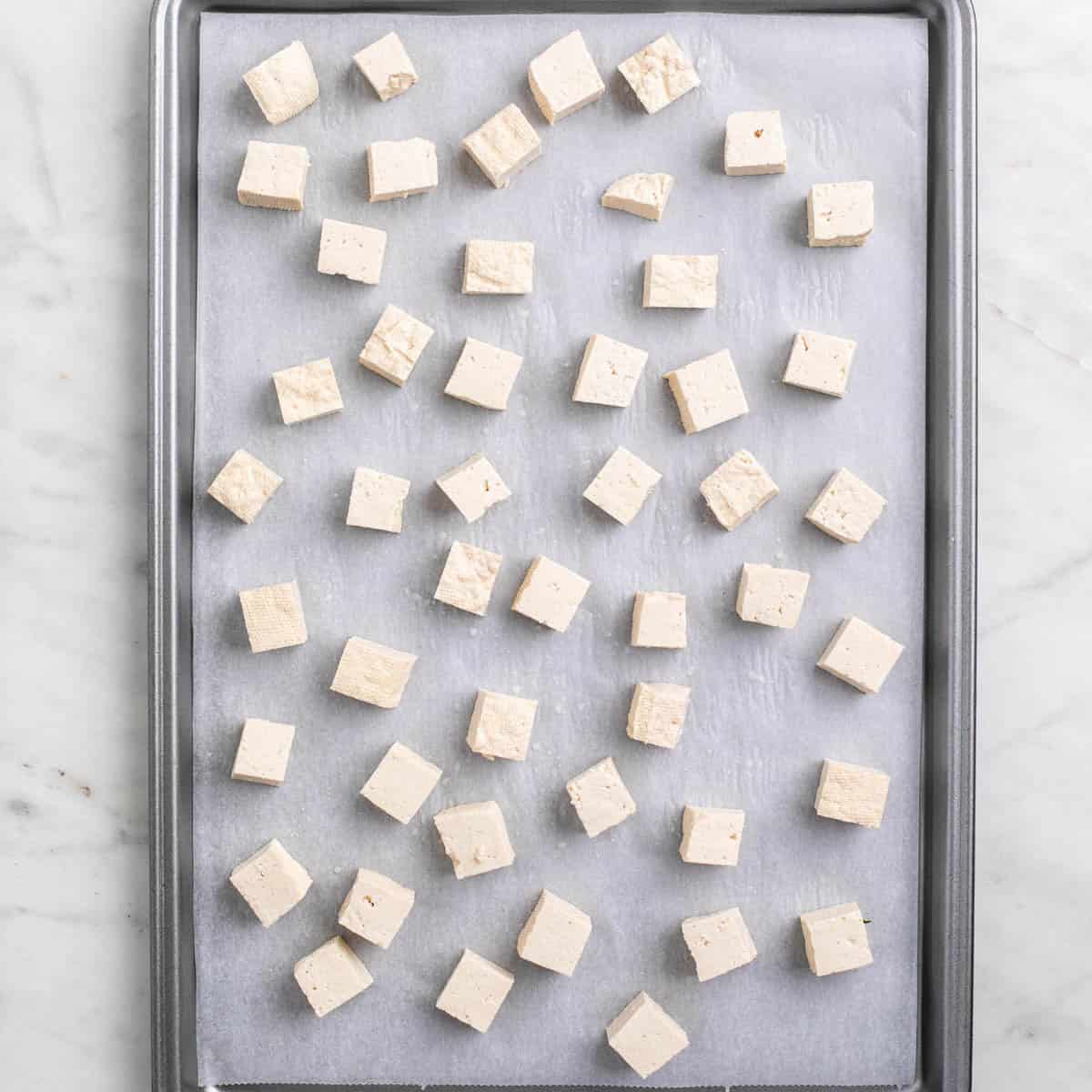 Tofu cubes on a lined baking sheet before freezing