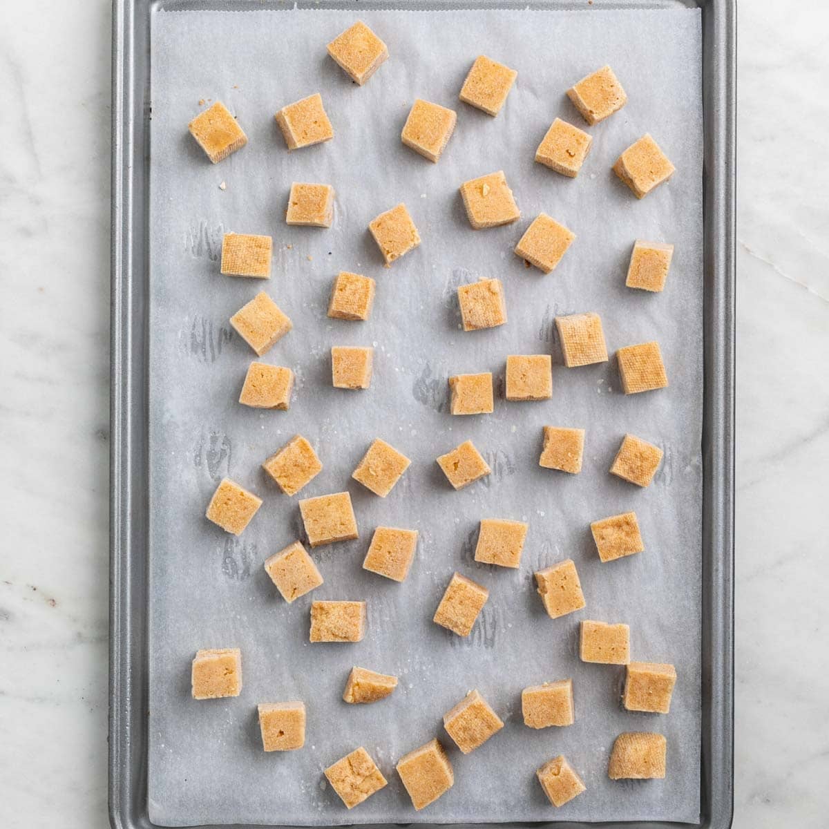 Frozen tofu cubes on a lined baking sheet