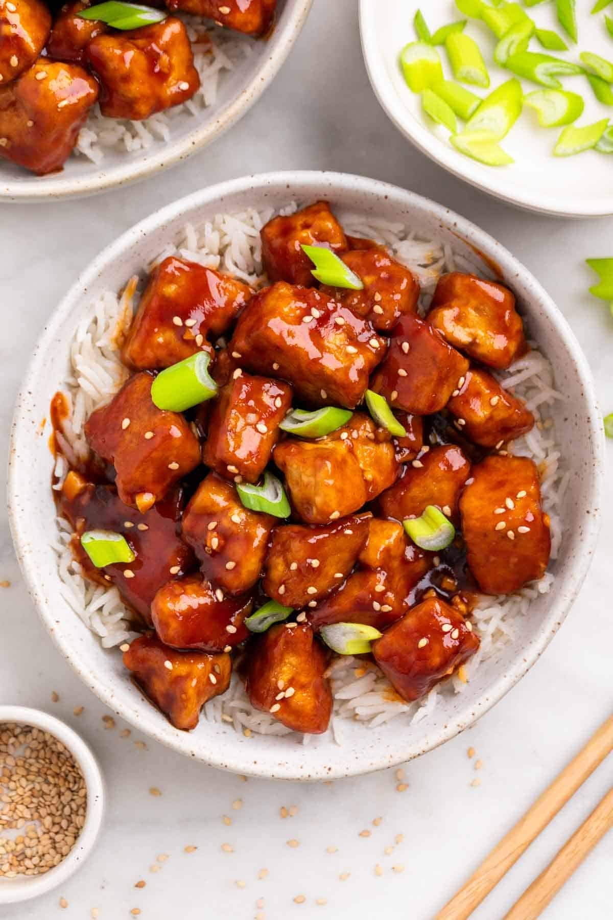 Bowl of Korean BBQ tofu served over rice with sesame seeds and green onions