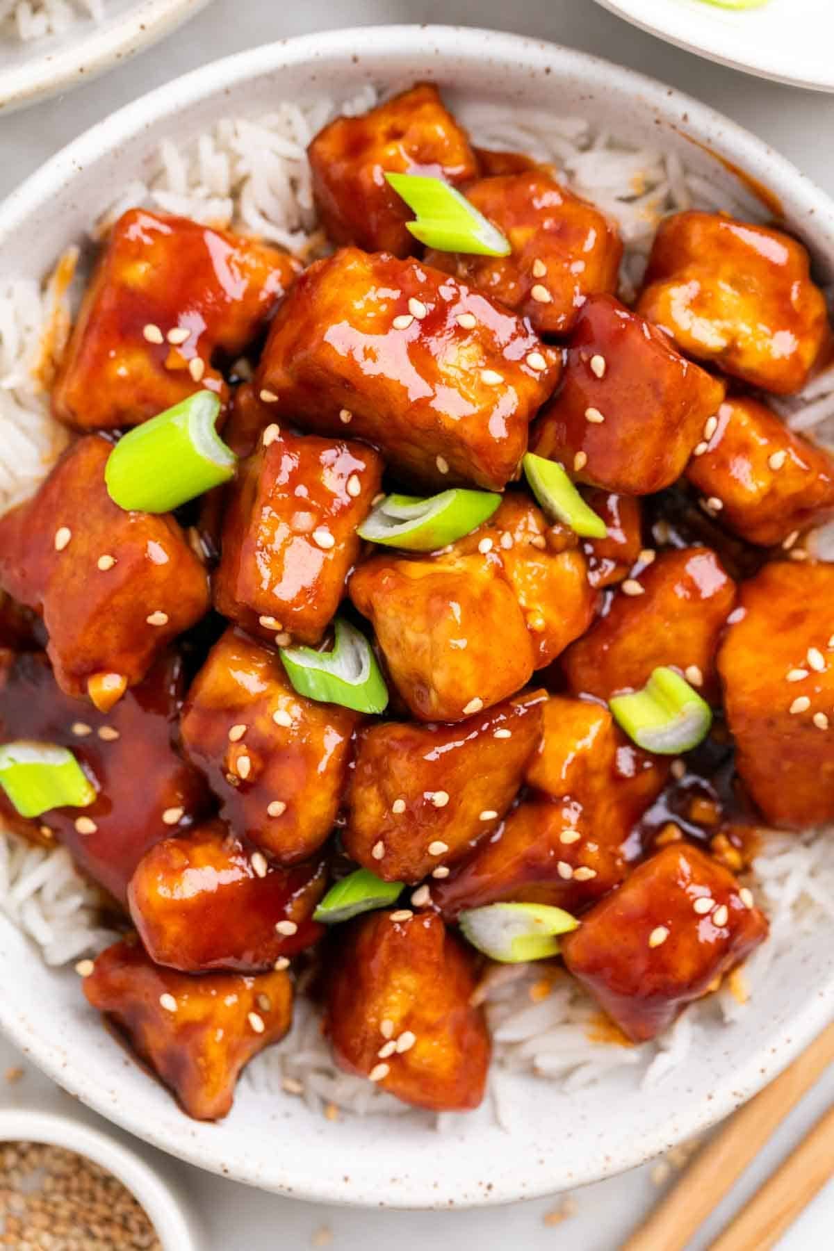 Crispy Korean BBQ tofu served over rice with chopsticks on the side