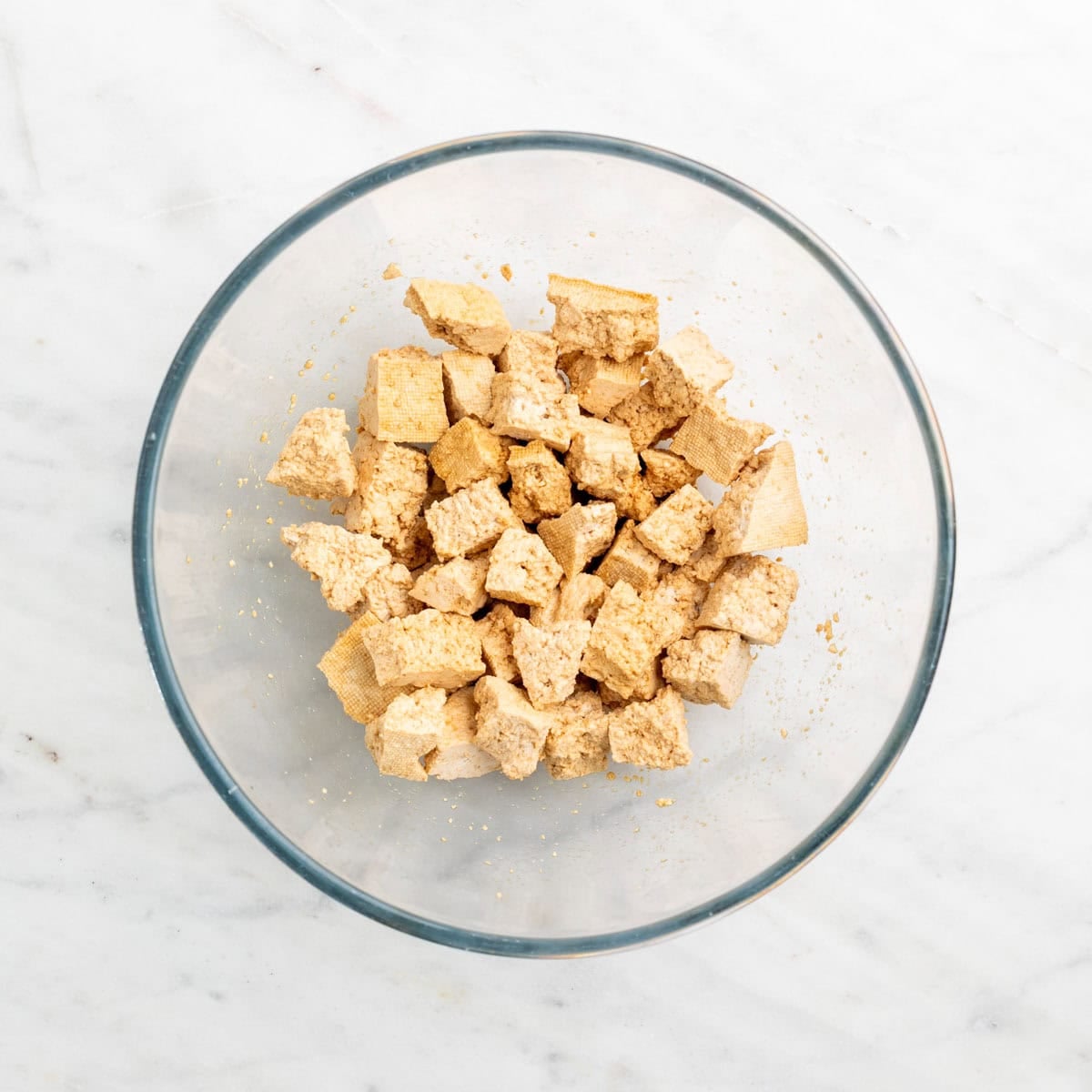 Torn tofu pieces coated with soy sauce in a bowl