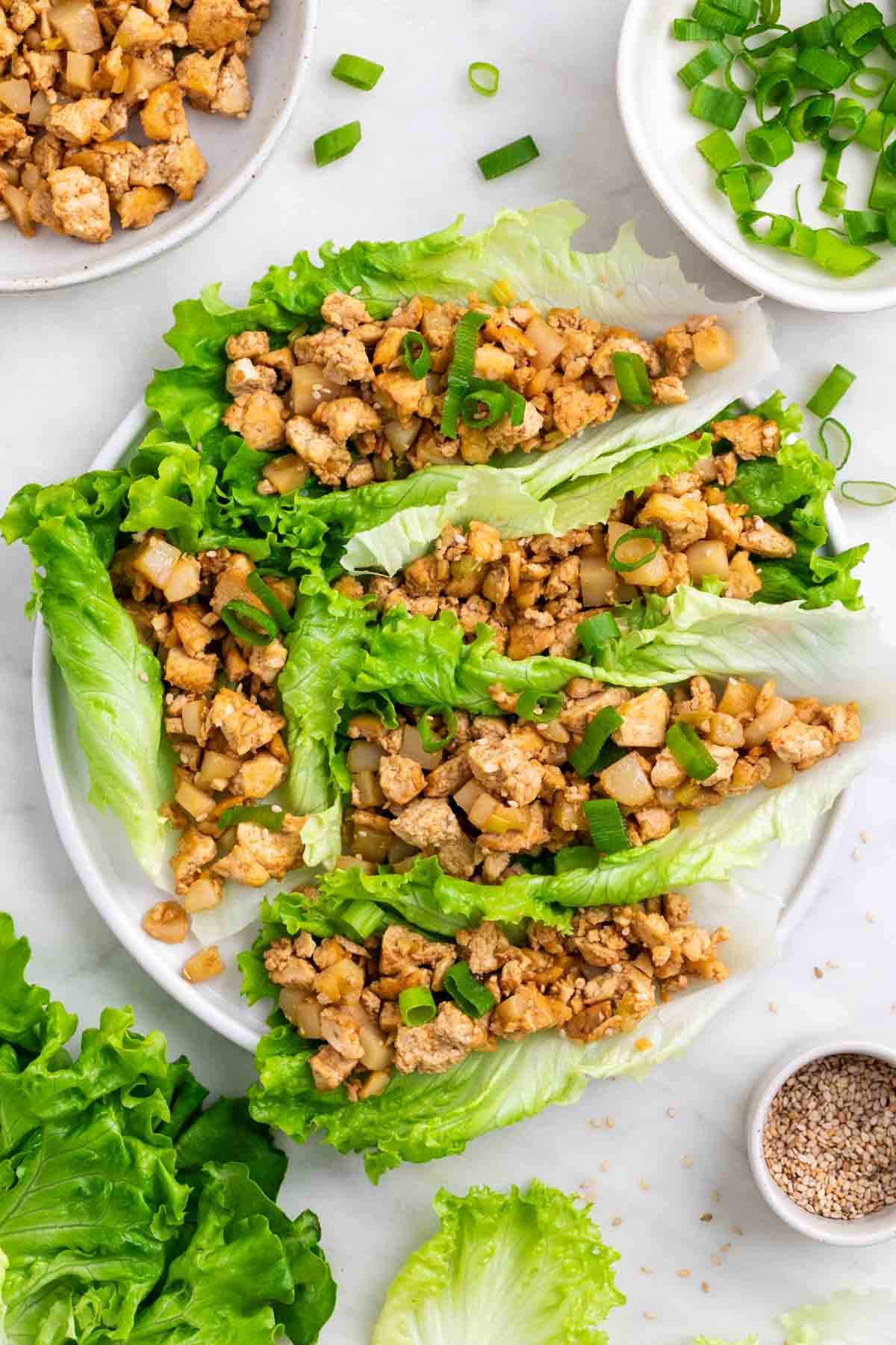 Lettuce wraps filled with tofu and topped with sesame seeds and green onions