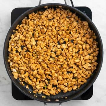 Crumbled tofu coated with sauce in a skillet
