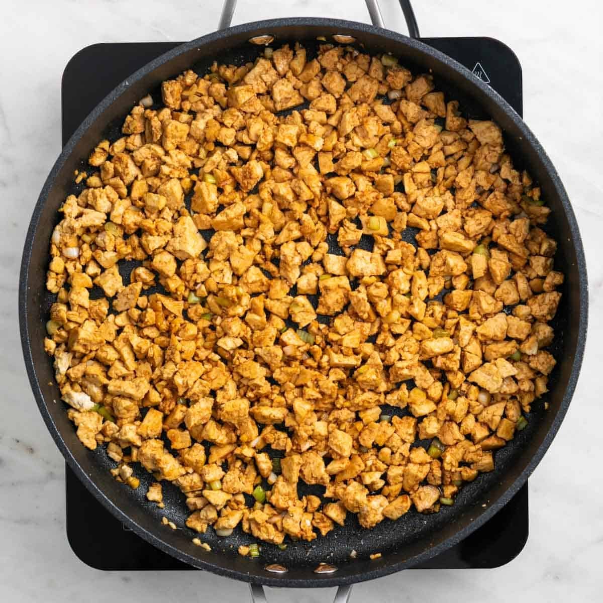 Crumbled tofu coated with sauce in a skillet