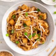 Close-up of tofu pad Thai garnished with green onions and chopped peanuts
