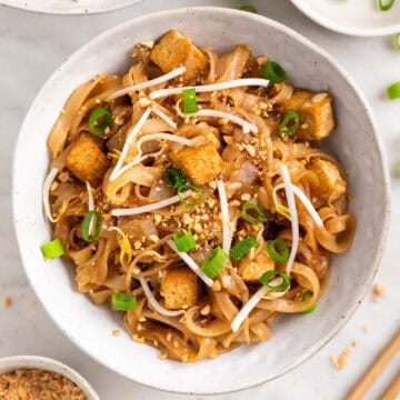 Close-up of tofu pad Thai garnished with green onions and chopped peanuts