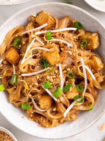 Close-up of tofu pad Thai garnished with green onions and chopped peanuts