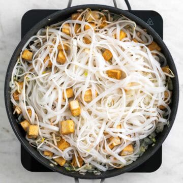 Tofu, vegetables, and rice noodles in a skillet