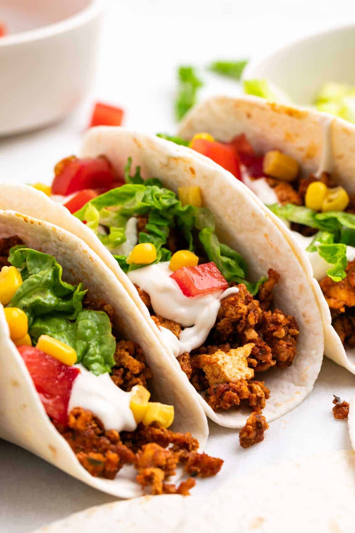 Tacos filled with tofu taco meat and toppings on top and around