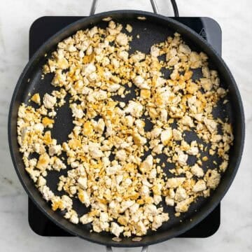 Crumbled tofu cooking in a skillet with oil