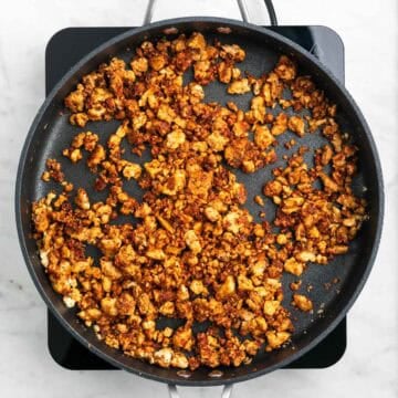 Crumbled tofu cooking with spices in a skillet