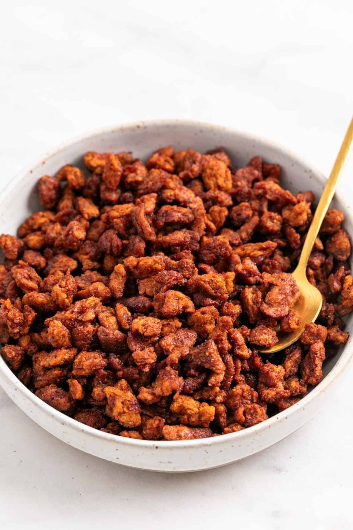Bowl of homemade vegan bacon bits with a golden spoon
