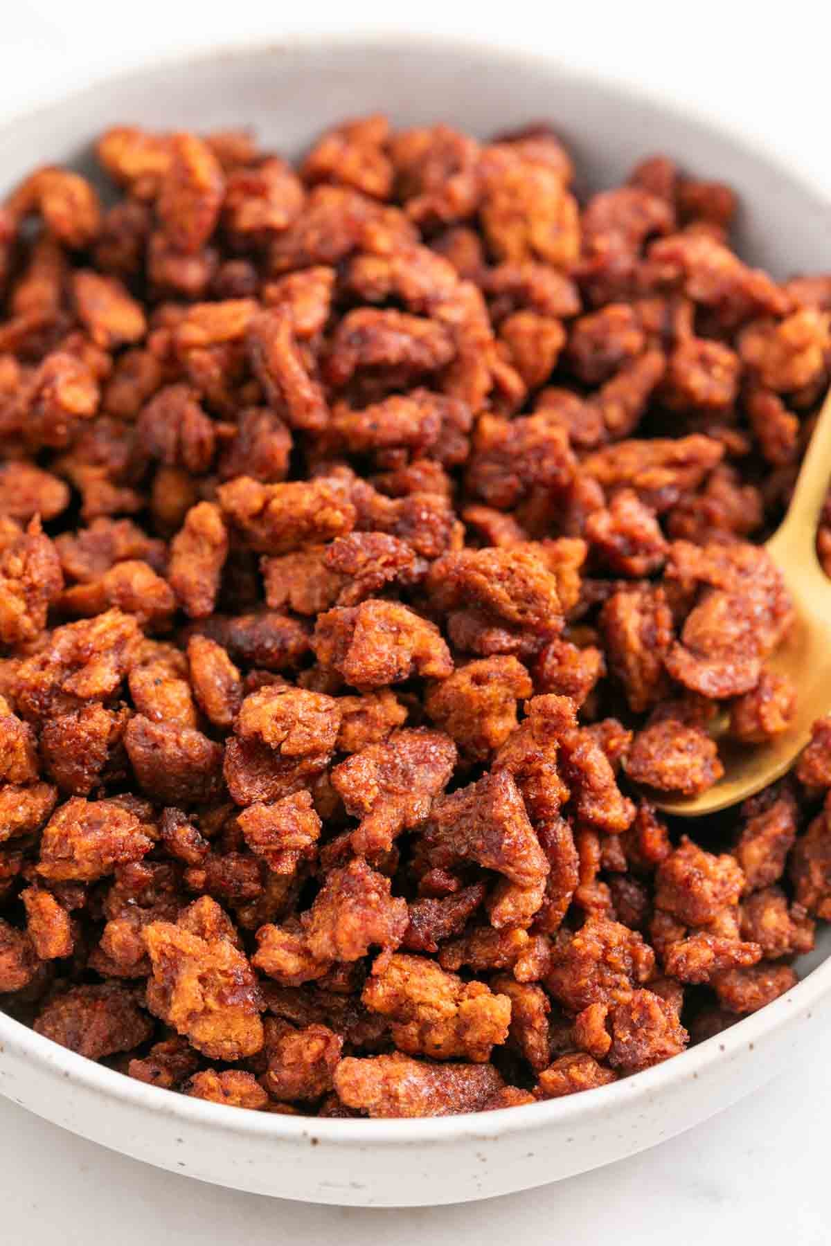 Crispy vegan bacon bits served in a bowl with a golden spoon