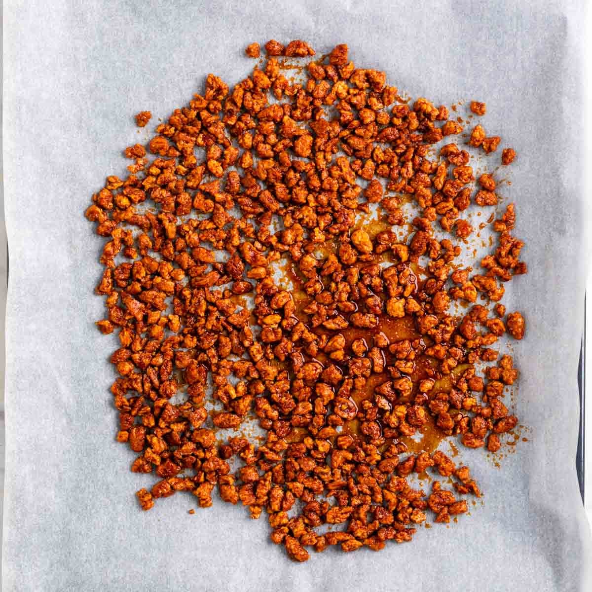 Marinated TVP spread onto a parchment-lined baking sheet before baking