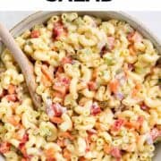 Homemade vegan macaroni salad served in a large bowl with a wooden spoon