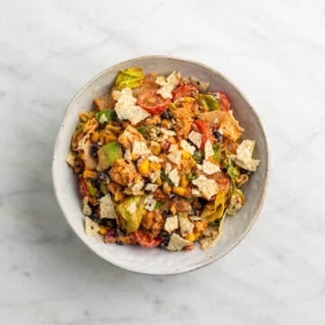 Vegan taco salad served on a plate with crushed tortilla chips