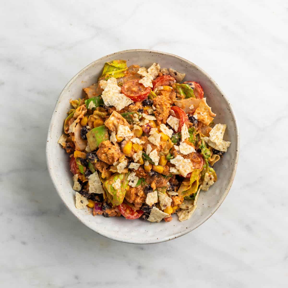 Vegan taco salad served on a plate with crushed tortilla chips