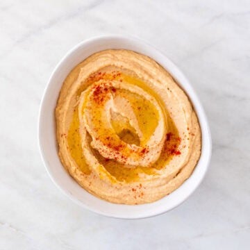 Homemade hummus in a bowl topped with extra virgin olive oil and paprika