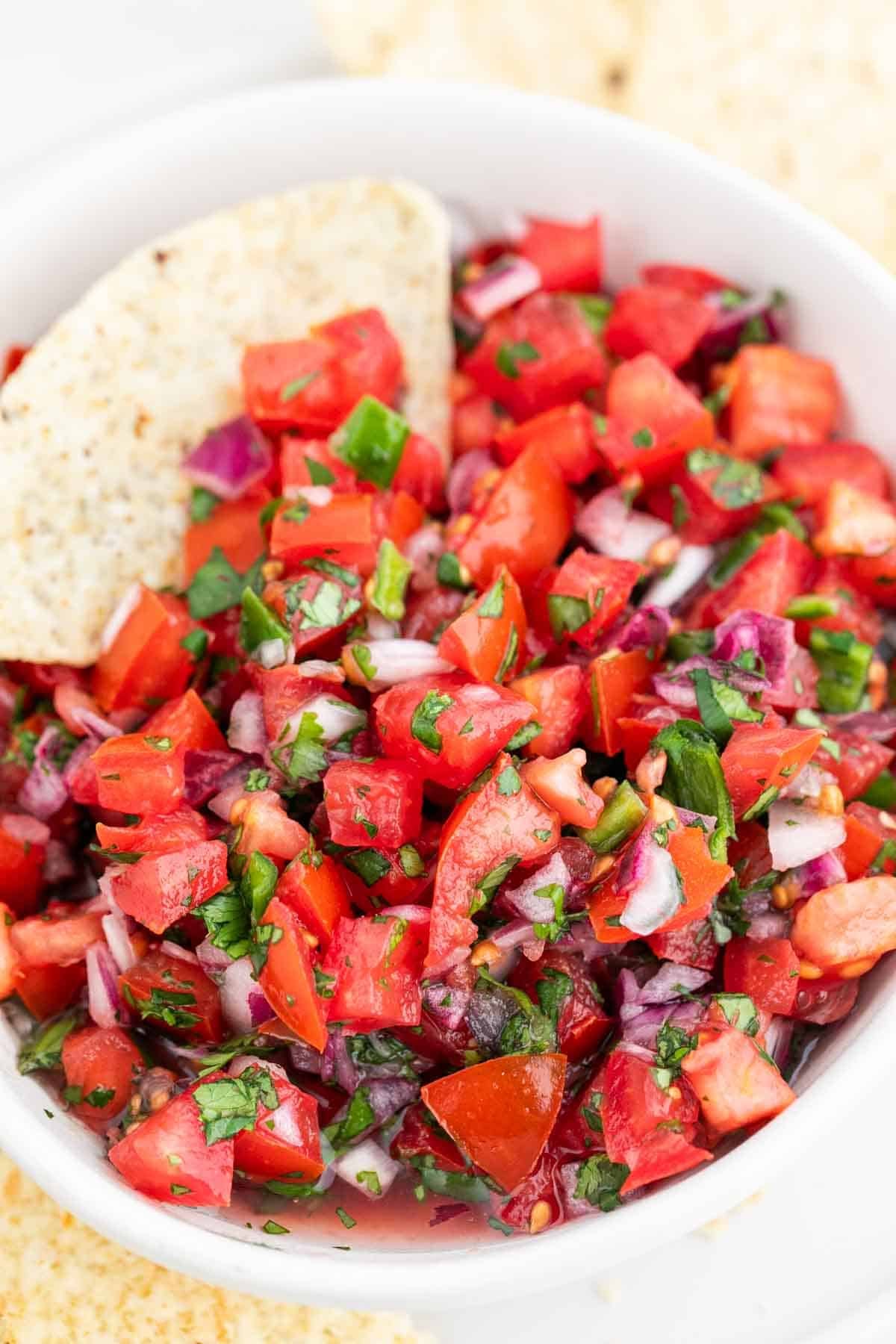 Fresh pico de gallo served with tortilla chips in and around the bowl