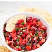 Pico de gallo topped with tortilla chips and surrounded by extra chips