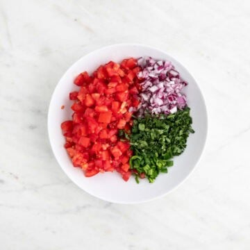 Chopped tomatoes, red onion, jalapeños, and cilantro in a bowl