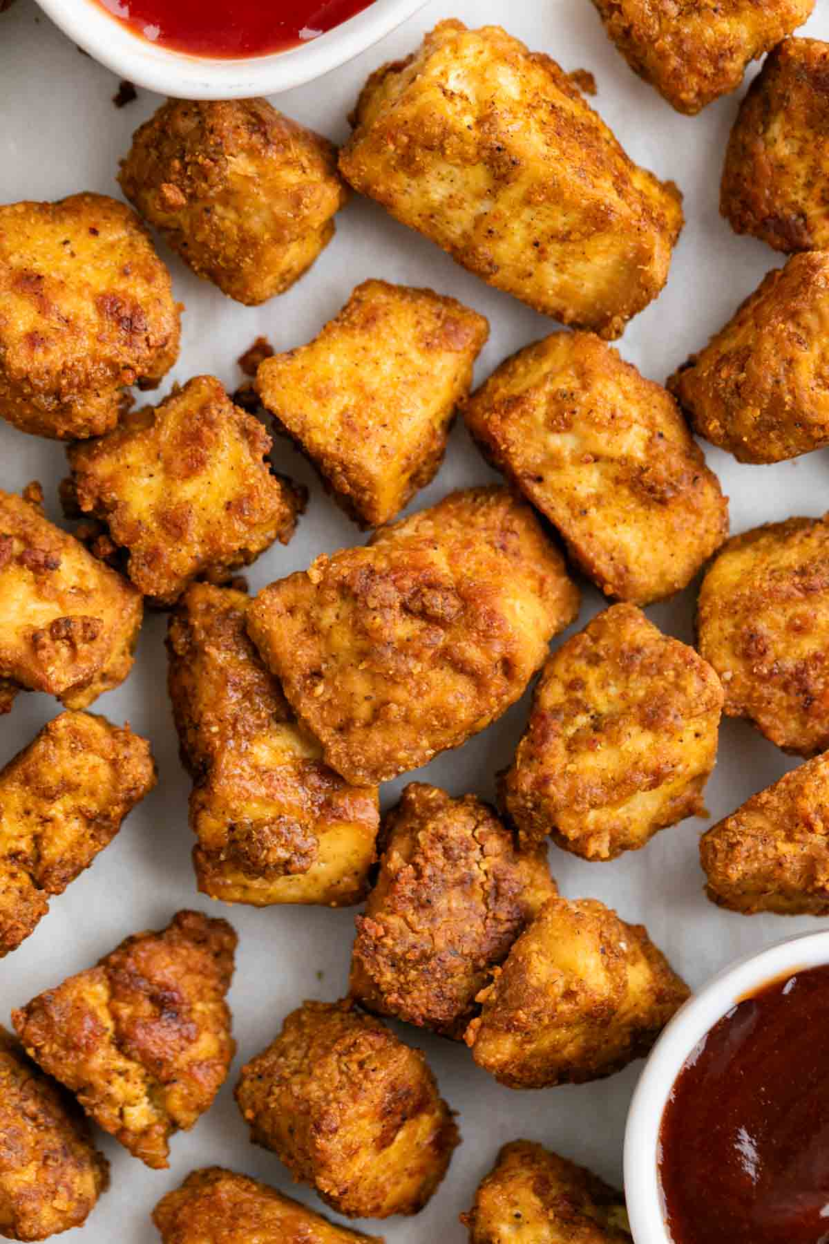 Crispy tofu chicken with BBQ sauce and ketchup on a white background