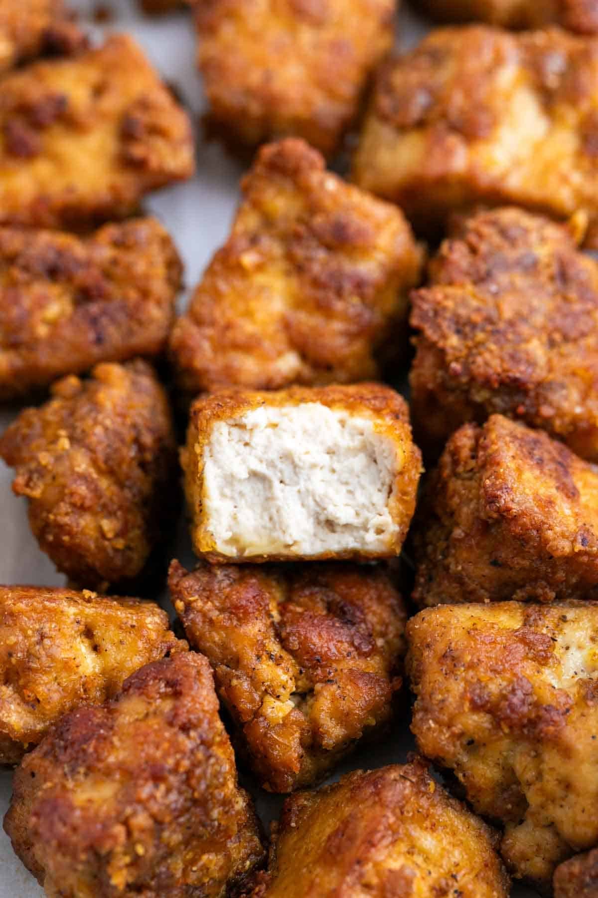 Baked tofu chicken with a bite taken out, revealing the inside texture