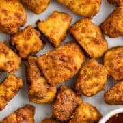 Crispy tofu chicken served with a bowl of BBQ sauce on a white surface