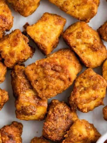 Crispy tofu chicken served with a bowl of BBQ sauce on a white surface