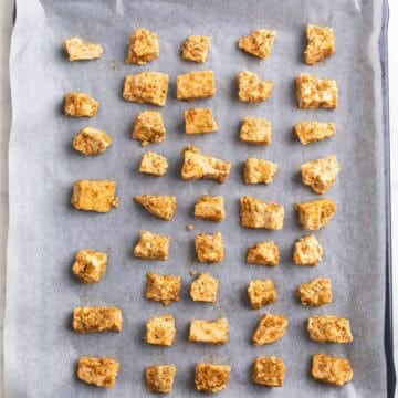 Seasoned tofu pieces arranged on a parchment-lined baking sheet