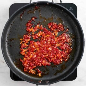 Tomato paste and red pepper flakes cooking with onion and garlic