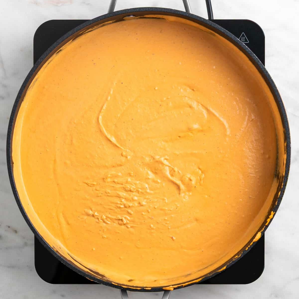 Creamy tofu tomato sauce cooking in a skillet