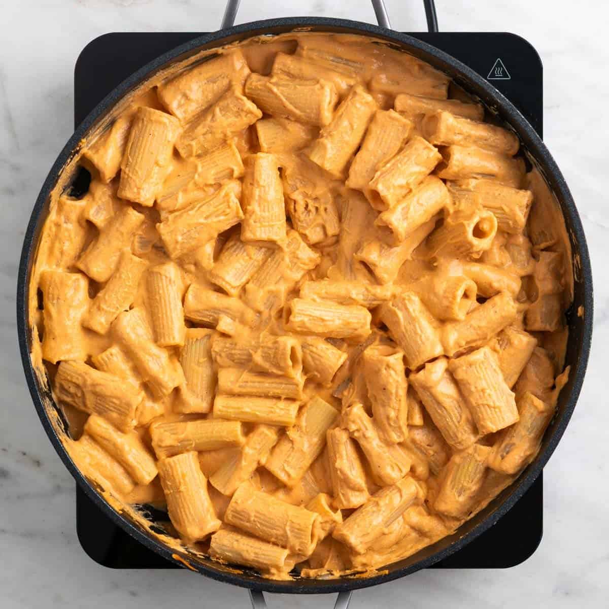 Rigatoni tossed with creamy tofu tomato sauce in a skillet