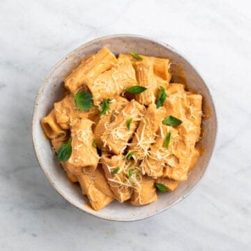 Tofu pasta topped with fresh basil and vegan Parmesan cheese