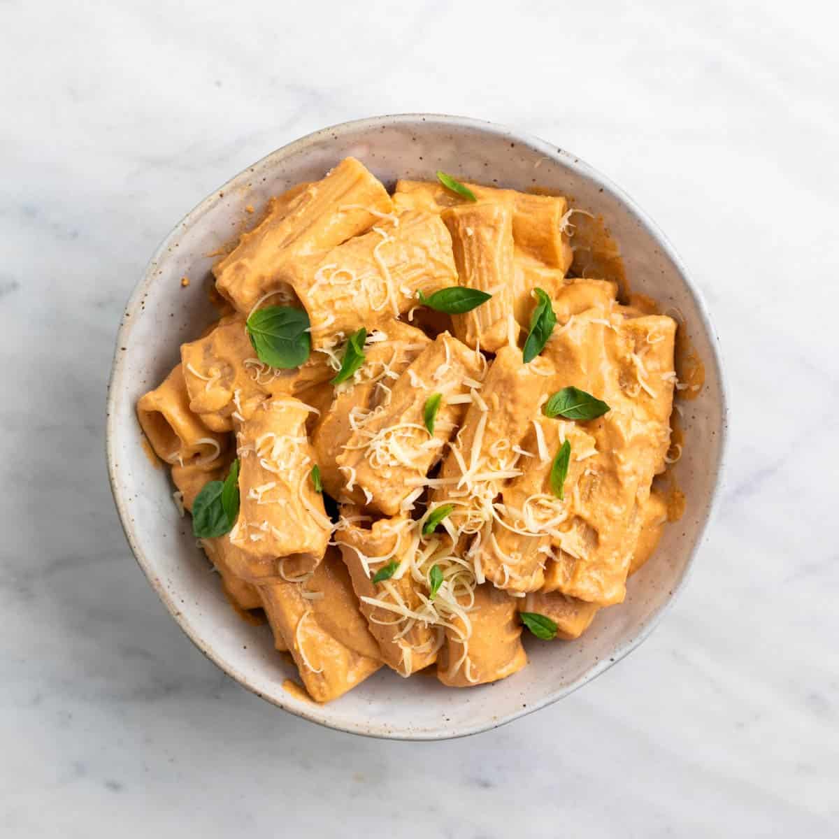 Tofu pasta topped with fresh basil and vegan Parmesan cheese