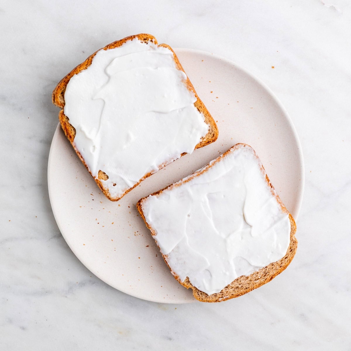 Vegan mayonnaise spread over one side of each toast slice