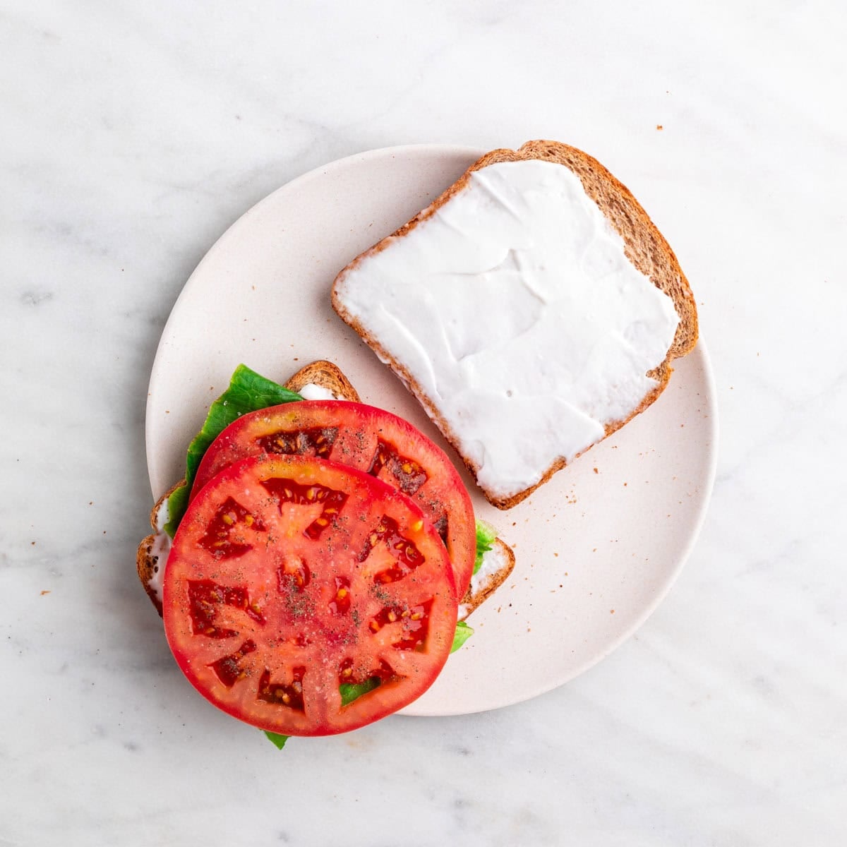 Lettuce and tomato layered on toast and seasoned with salt and pepper