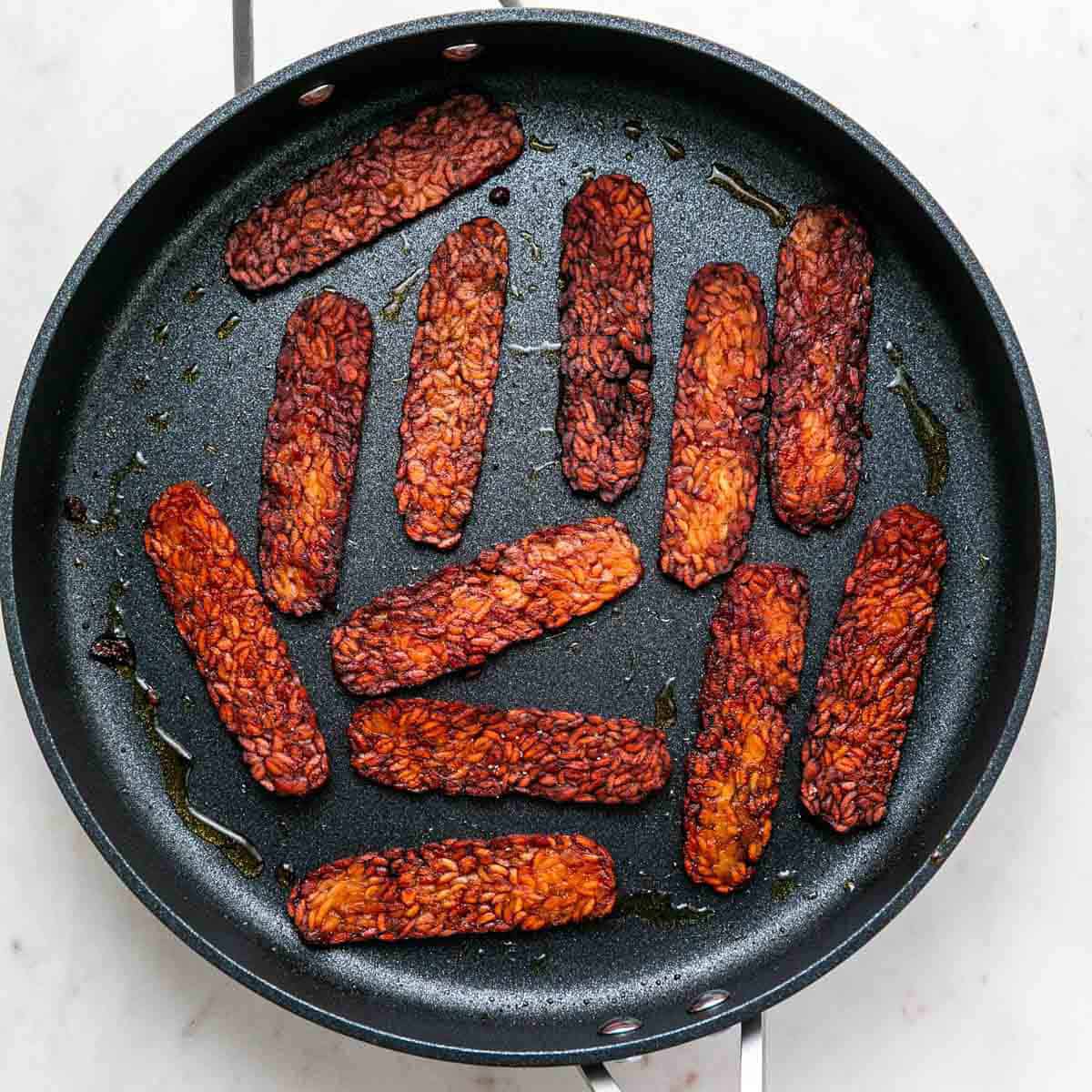 Vegan bacon cooking in a skillet
