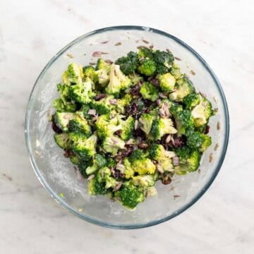 Vegan broccoli salad tossed with creamy dressing in a large mixing bowl