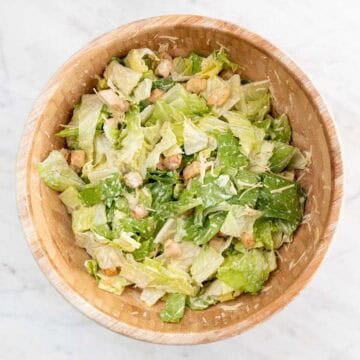 Vegan Caesar salad tossed with creamy dressing in a large bowl